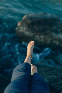 Pies al borde de una roca frente al agua profunda, símbolo del salto interior entre el miedo y la entrega